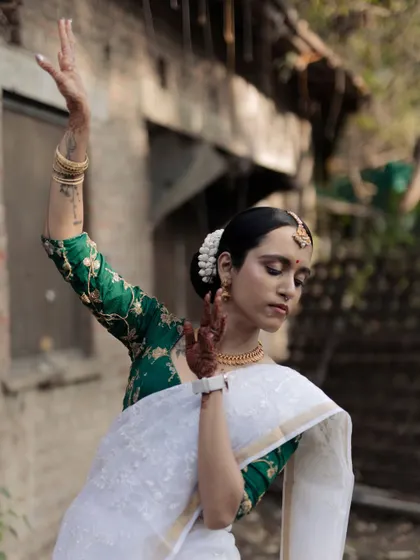 A graceful portrait of a bride in a classic South Indian dance pose. Dressed in a white and green saree, she embodies elegance and cultural richness.