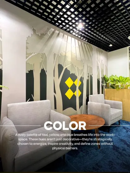 A comfortable lounge area at VentureX where color is used strategically. The blue carpet and nature-inspired wall graphic with yellow brand accents create an energizing and creative zone without physical barriers.