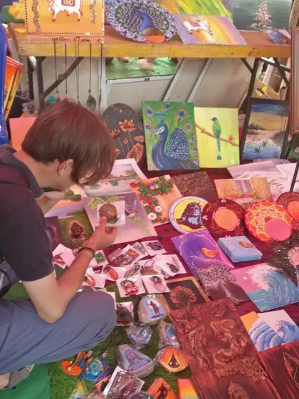 A visitor taking a closer look at my small stone paintings and other handcrafted items at my stall.