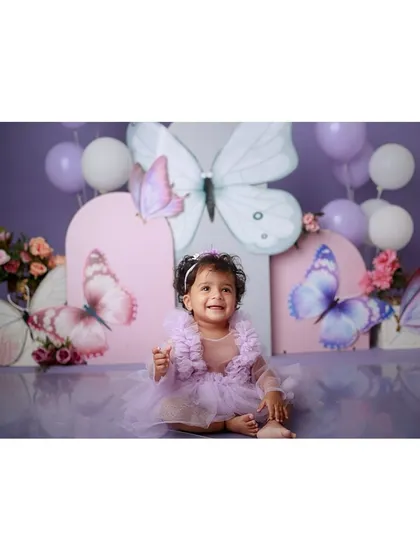 A wide shot of the enchanting butterfly theme, complete with a purple dress, balloons, and large butterfly props.