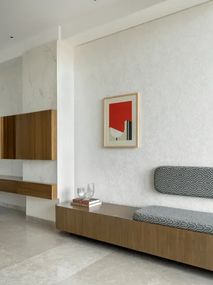 Clean lines and honest materials define this entryway. A long, floating wooden bench with integrated seating provides a functional and minimalist welcome. The space is kept deliberately simple, allowing the textures of the wall finish and a single piece of art to make a quiet statement.
