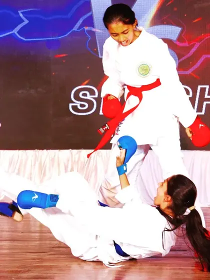 A decisive moment in a Kumite demonstration. One student executes a controlled sweep, showcasing the practical application of techniques learned in the dojo.