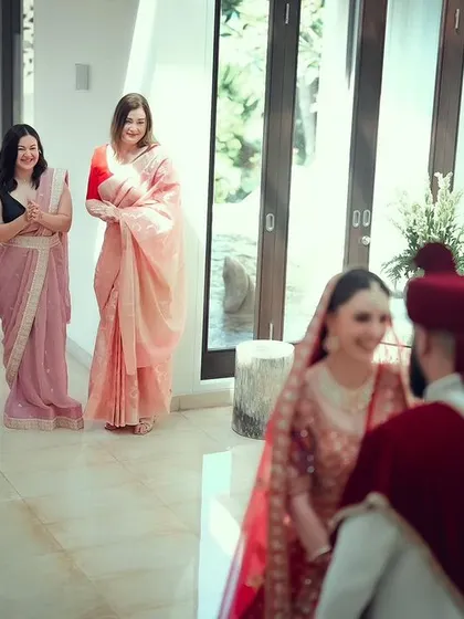 A candid moment of the bride's first look at the groom, with her bridesmaids sharing in her happiness.