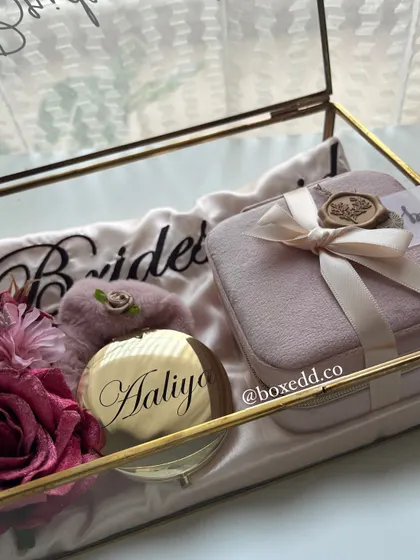 A close-up of the personalized details in our glass bridesmaid box. The engraved mirror with 'Aaliya' and the custom 'Bridesmaid' robe show how we make each gift feel unique and special.