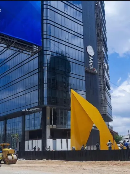 The full-scale "Yello" installation during construction. This image shows the transition from concept to reality, as the 30-foot-tall sculpture is installed in front of the new office building in Hyderabad, becoming a permanent landmark.