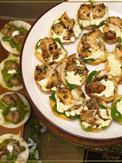 An overhead view of our canapés, featuring grilled chicken on a bed of greens and pesto. Each bite is carefully constructed to deliver a perfect balance of flavors.