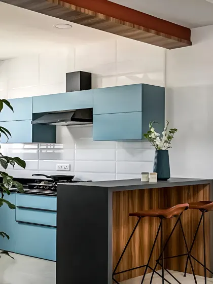 A contemporary kitchen design with a breakfast bar for casual dining. The combination of powder blue cabinets, a dark countertop, and wood accents creates a fresh and modern aesthetic.