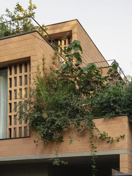The upper levels of the Debris Block House feature balconies with integrated planters, allowing residents to be surrounded by greenery even on a compact urban plot.