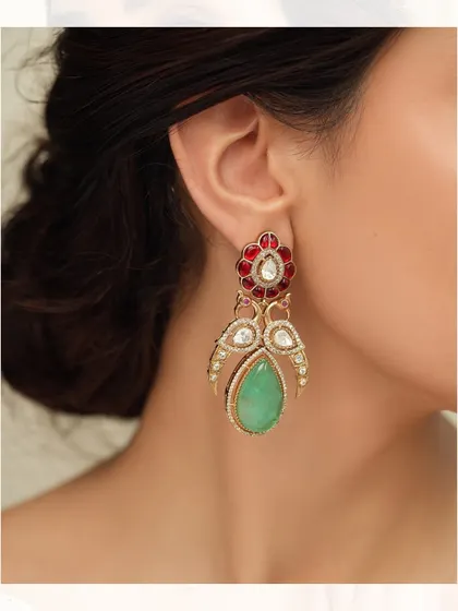 A pair of earrings featuring a peacock-like design with a large green teardrop stone and red enamel work.