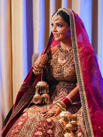 A classic seated bridal portrait. Her traditional pose, holding her kalire, and the soft lighting create a timeless and graceful image.
