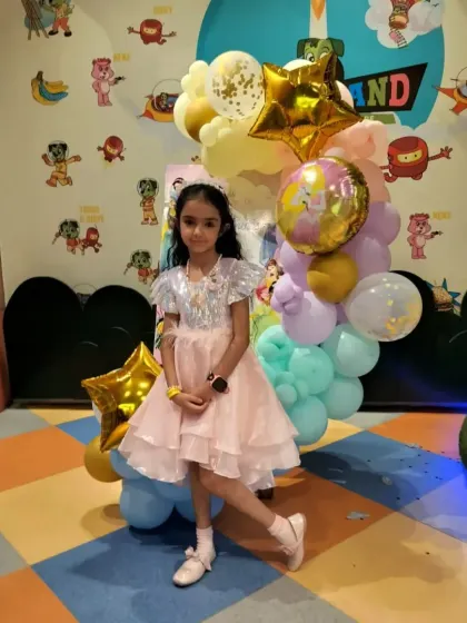 A birthday girl poses by a beautiful balloon arrangement. Our themed decorations provide plenty of wonderful spots for memorable birthday photos.