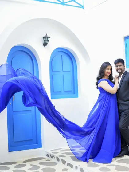 A beautiful pre-wedding photo with a flowing blue gown against a Santorini-themed backdrop. The movement of the fabric is just magical.