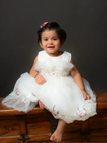A delightful portrait of a toddler in a beautiful white dress, captured during a family session in the studio.