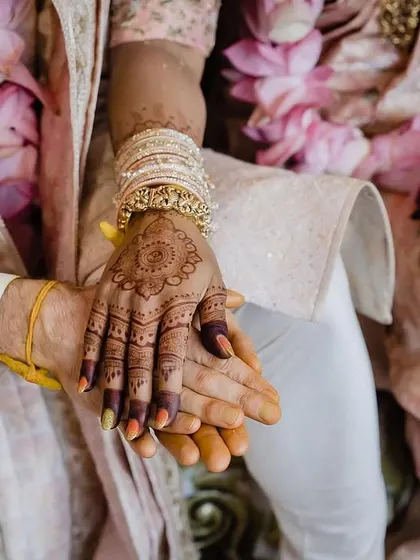 A close up of the couple holding hands, focusing on the bride's beautiful mehndi. This simple, symbolic gesture is a powerful representation of their union.