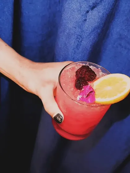 A vibrant pink cocktail, garnished with fresh berries and a slice of orange. It's as delicious as it is photogenic.