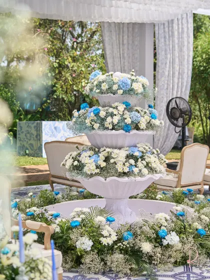 The centerpiece of the carnival: a three-tiered white fountain overflowing with white, blue, and light green flowers. This custom installation was a major focal point.