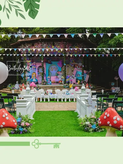 Another view of the grand Alice in Wonderland setup, showcasing the lush green lawn, themed props, and colorful bunting.