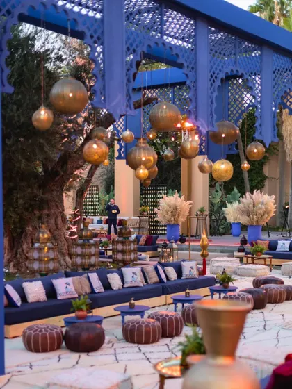 A Moroccan-inspired Sangeet lounge in Majorelle blue, with low seating, leather poufs, and hanging brass lanterns creating an authentic oasis vibe in Marrakech.