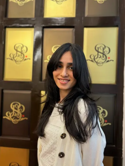 A happy client showing off her new layered cut and bangs. This style is designed to flatter her face shape and bring out her natural beauty.