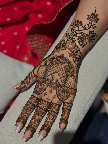 A stunning Karwachauth design featuring a peacock in a jharokha (window) with a floral vine extending up the arm. It's the perfect blend of elegance and tradition.