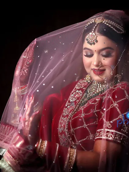 A serene bridal portrait with the bride looking down, her face softly lit under the veil. This classic pose exudes grace and elegance.
