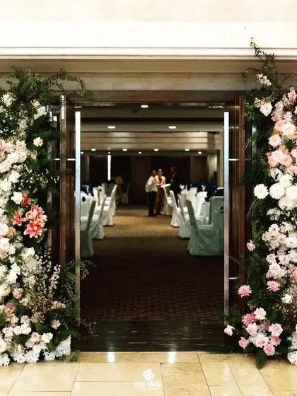 A beautiful welcome for guests at Four Points Navi Mumbai. The entrance to the banquet hall is framed with large, lush arrangements of white and pink flowers.