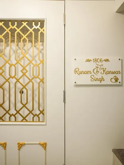 A close-up of the custom acrylic nameplate, designed to match the white and gold theme of the entrance.