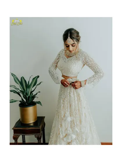A beautiful bridal portrait. The bride, Hayaati, is getting ready, her off-white lehenga looking ethereal. This shot captures a quiet moment of preparation.