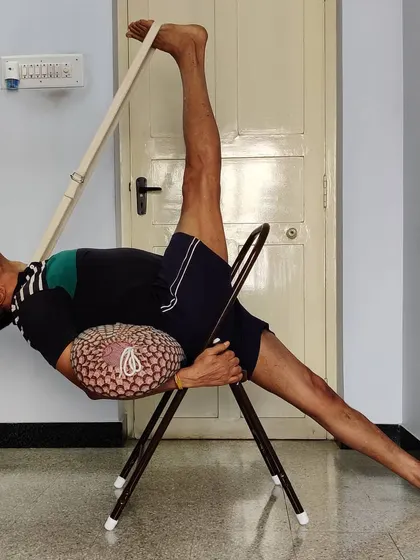Eka Pada Urdhva Dhanurasana (One-Legged Upward Bow Pose) with a chair, bolster, and belt. This shows how multiple props can be used to safely explore very advanced backbends.