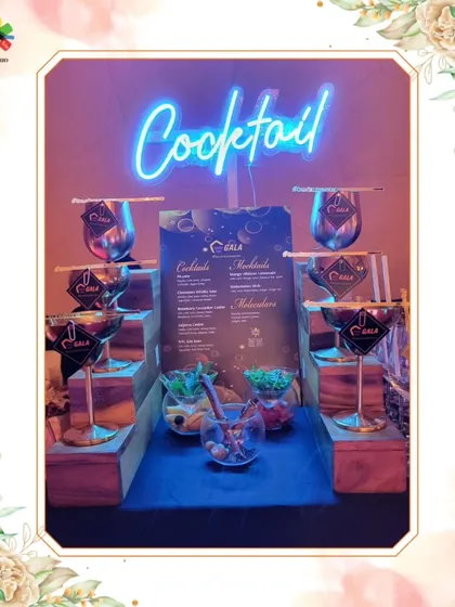 A chic and modern cocktail bar setup with a blue neon sign. The tiered display of metallic glassware adds a touch of contemporary elegance, perfect for a stylish reception.