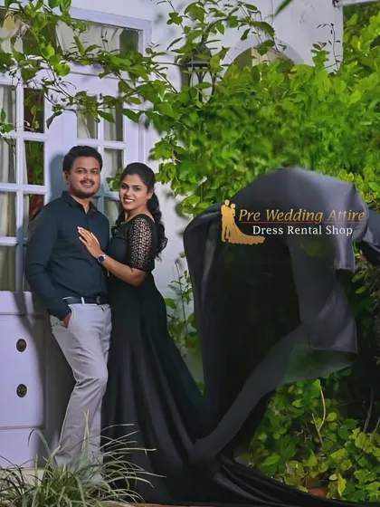 A relaxed couple's portrait. The woman wears a black trail gown, and the man is in a casual shirt and pants, showing that these dramatic gowns can also be styled for more informal shoots.