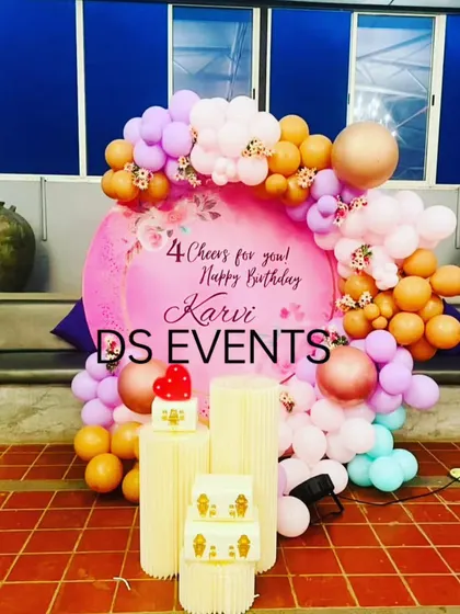 A soft and pretty pastel balloon decoration for a 4th birthday. The organic arrangement of balloons in peach, lilac, and mint green around a custom circular backdrop creates a cheerful and modern party look.