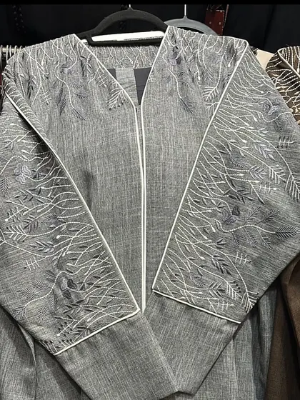This grey zip up abaya features intricate white embroidery in a beautiful branch and leaf pattern across the sleeves and front panels.