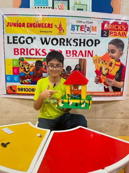 A student points proudly to the house he built during our Bricks 2 Brain LEGO workshop.