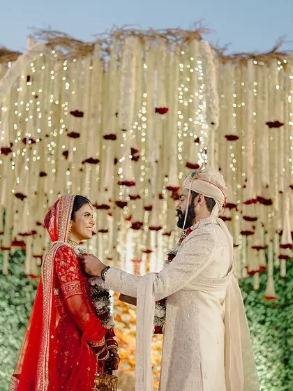 A beautiful candid moment of the couple under the dense floral canopy of the Kalpavṛkṣa mandap.