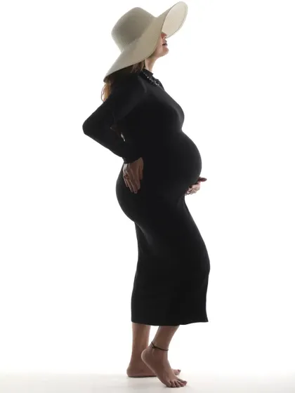 A striking silhouette of a mom-to-be against a white background. This high-key lighting technique creates a bold and modern portrait that is both artistic and timeless.