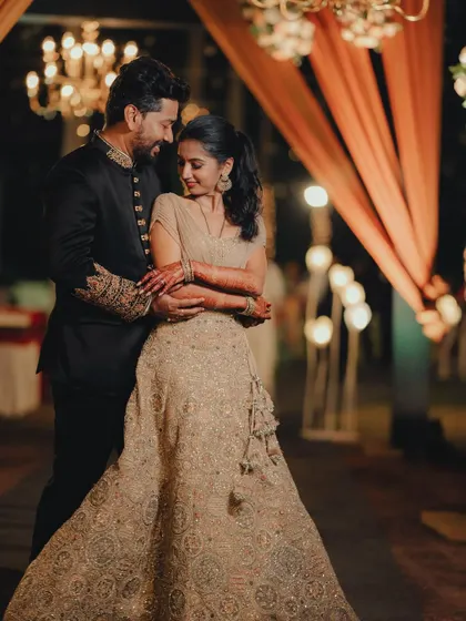 A romantic embrace between the couple, with the soft lighting of their chic reception in the background.