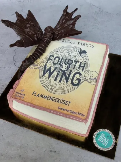 A different perspective of the 'Fourth Wing' book cake, showing the full sculpture of the chocolate dragon and the detailed, edible pages of the book.