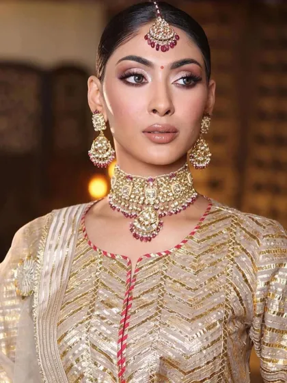 A soft and classic bridal look with gold and ruby jewelry. The makeup focuses on a warm, bronze eye and a defined lip, a universally flattering combination.