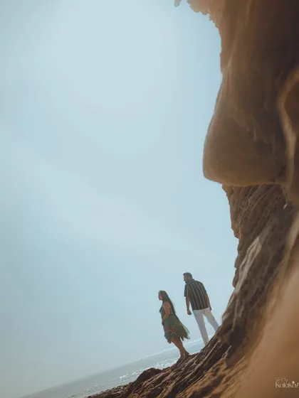 A dramatic low-angle shot using the rock formations to frame the couple against the vast sky, creating an epic, adventurous feel.