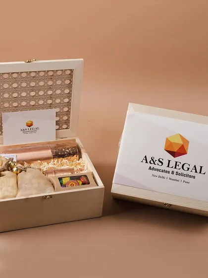 A premium Diwali gift set for A&S Legal, featuring a custom-branded pinewood box with a cane lid. This hamper includes a copper bottle and other curated items for a sophisticated corporate gift.