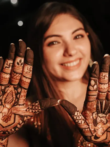 A close-up of the bride's fingers, showing the intricate details and auspicious symbols.