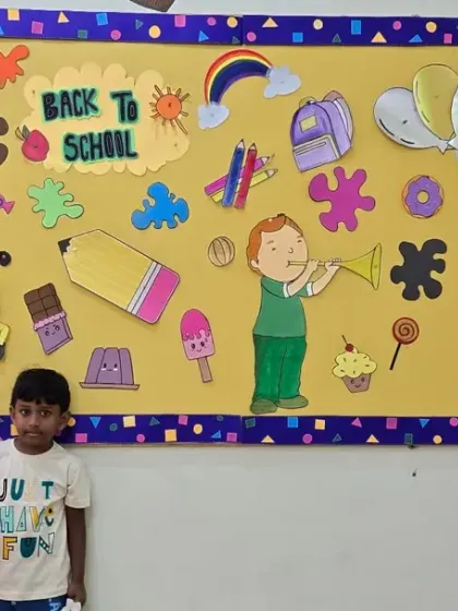A new student posing by the 'Back to School' board, ready to start his learning adventure with us.