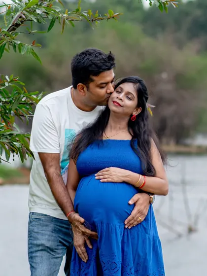 A sweet kiss on the cheek makes for a timeless and romantic maternity photo. This was captured by a lake, adding a serene element to the outdoor session.