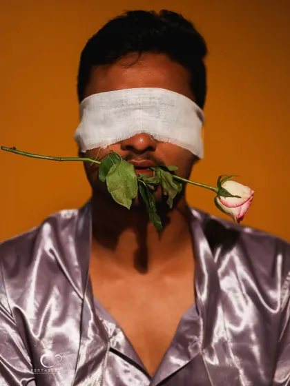 The contrast between the soft rose and the blindfold is the central theme of this artistic and thought-provoking portrait.