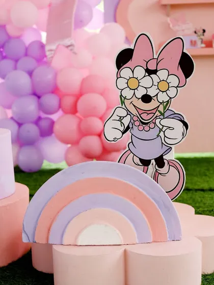 A whimsical Minnie Mouse cutout with daisy sunglasses, paired with a pastel rainbow prop. This fun detail adds a modern and playful twist to a classic theme.