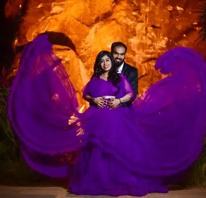 The dramatic wings of this purple gown create a stunning heart shape around the couple, making for a truly unique and memorable pre-wedding photograph.