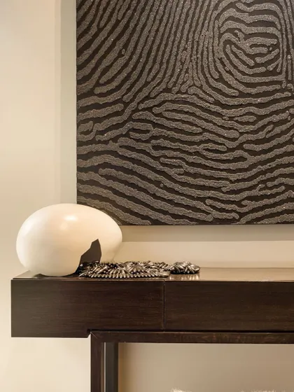 A close-up on a console table vignette. The abstract, textured artwork is complemented by a smooth, sculptural object, creating a beautiful contrast of materials and forms that adds depth and interest to a quiet corner.