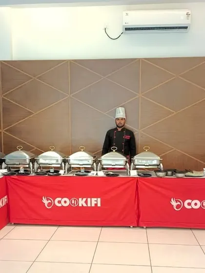 A well-organized buffet setup in a party hall with a modern aesthetic, ready for a house party.