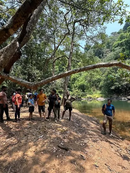 A group photo under a large, interestingly shaped tree by the river.